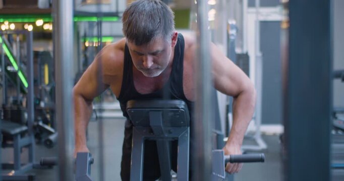 Gym workout. Back exercise. 4k footage of a middle aged Caucasian man trains his back muscles in the gym. Middle-aged Caucasian man trains back with precise form during an intense gym workout.