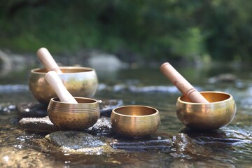 Tibetan singing bowls with mallets on stones in river