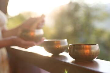 Woman with singing bowls outdoors on sunny day, selective focus
