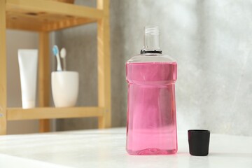 Bottle and cap of mouthwash on white counter in bathroom. Space for text