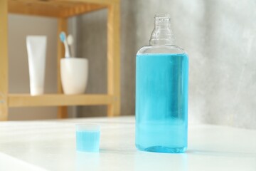 Bottle and cap of mouthwash on white counter in bathroom. Space for text