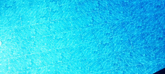 Obraz premium Blue water surface ripples and waves background. Flowing water waves with light reflections, swimming pool, sea and ocean. Clear water current, splashes and waves top view. Summer vacation.