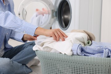 Woman with laundry near washing machine indoors, closeup