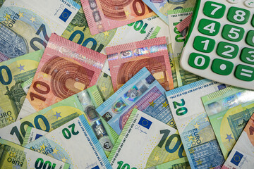 Stack of Euro banknotes with blue calculator symbolizing finance, accounting and money planning