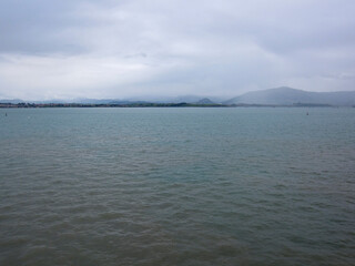 Fototapeta premium A view of a body of water with mountains in the background under a cloudy sky.