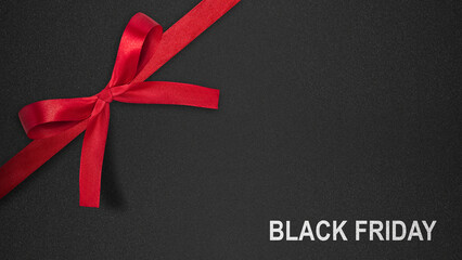Closeup view of red ribbon with text of Black Friday on a black background. Copy space. Flat lay....