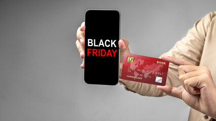 Human hand holding a credit card and a cellphone with the text of Black Friday on the screen....