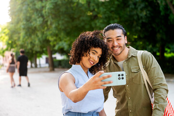 Happy interracial couple taking a selfie in the park