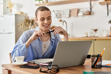 Young man works cheerfully at home while sipping coffee and smiling at the laptop