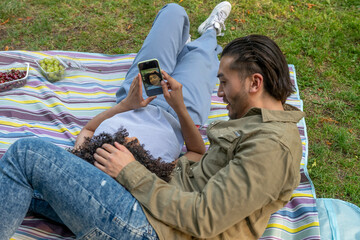 Interracial couple taking a selfie during romantic picnic in park