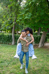 Naklejka premium Interracial couple having fun in the park, piggyback ride and laughter