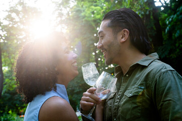 Interracial couple toasting with wine glasses in a park
