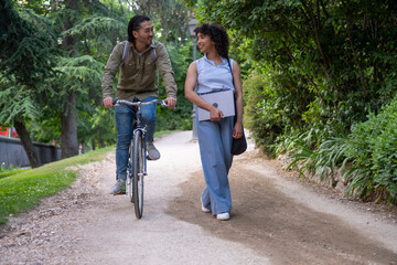 Obraz premium Interracial couple enjoying walk and ride in park with bicycle and laptop