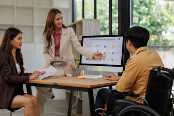 An inclusive modern office environment with a diverse team collaborating. A person in a wheelchair actively engages with colleagues.
