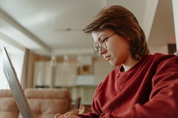 A young woman works on her laptop in a cozy living room, capturing the modern freelance lifestyle....
