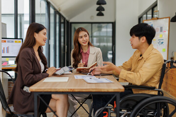 An inclusive modern office environment with a diverse team collaborating. A person in a wheelchair actively engages with colleagues.
