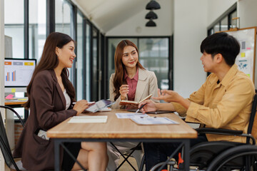 An inclusive modern office environment with a diverse team collaborating. A person in a wheelchair actively engages with colleagues.
