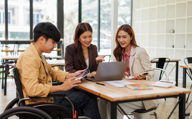 An inclusive modern office environment with a diverse team collaborating. A person in a wheelchair actively engages with colleagues.
