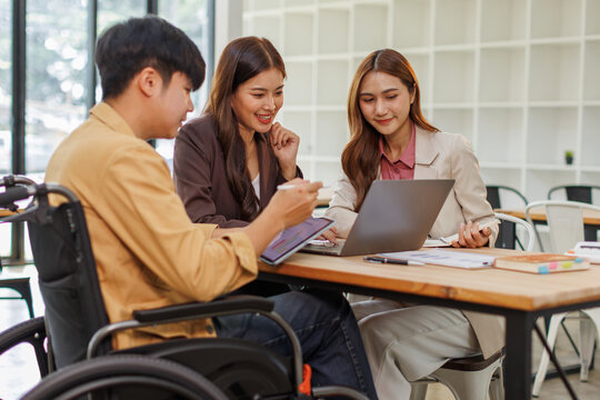 An inclusive modern office environment with a diverse team collaborating. A person in a wheelchair actively engages with colleagues.
