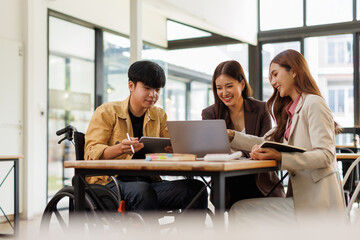 Asian Male Manager On A Wheelchair Sitting With His Colleagues At Workplace
