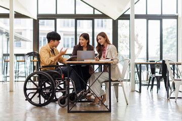 Asian Male Manager On A Wheelchair Sitting With His Colleagues At Workplace