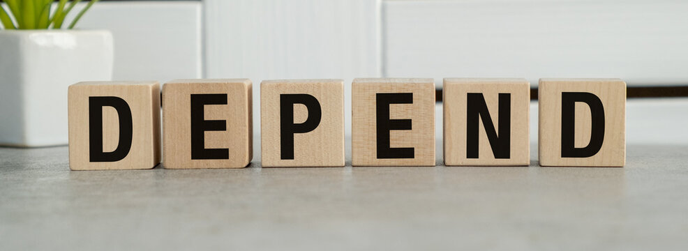 The word depend is written in wooden blocks on a gray surface