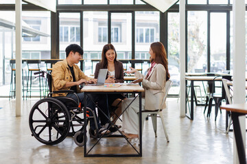 Fototapeta premium Asian Male Manager On A Wheelchair Sitting With His Colleagues At Workplace 