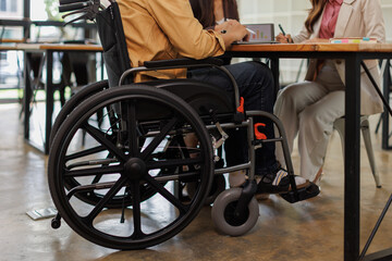 Obraz premium Group of business people in a meeting with man on a wheelchair for inclusion. Young businessman greeting business partner and team. Coworker on wheelchair 