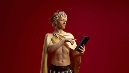 Man in Roman toga as Caesar using digital tablet with serious expression. Concept of technology...