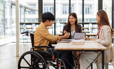 Group of business people in a meeting with man on a wheelchair for inclusion. Young businessman greeting business partner and team. Coworker on wheelchair
