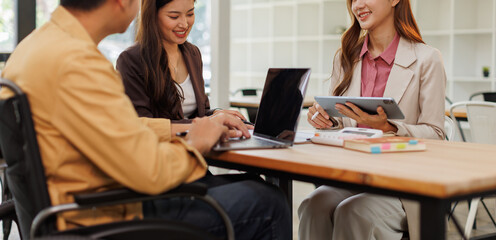 Group of business people in a meeting with man on a wheelchair for inclusion. Young businessman greeting business partner and team. Coworker on wheelchair
