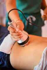 Beautician using ultrasound cavitation device for body contouring treatment