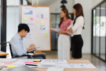 Happy business man on wheelchair and her female colleague cooperating while working on paperwork in the office.
