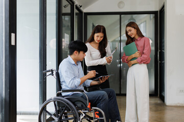 Group shot of diverse business people, disabled asian man on wheelchair chatting with colleagues together at meeting room at office
