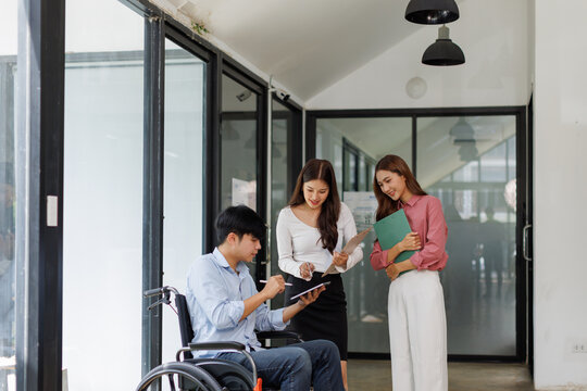 Group shot of diverse business people, disabled asian man on wheelchair chatting with colleagues together at meeting room at office
 - Powered by Adobe