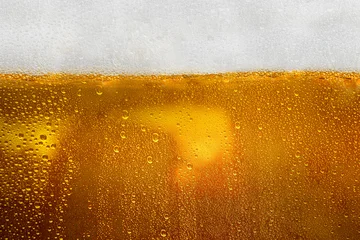 Fotobehang Bar Closeup view of refreshing golden beer with foam in a cold mug. Abstract and textured background. Concept of refreshing alcohol drink, Oktoberfest, summer, or party  © Leo Lintang