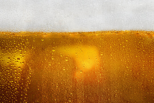 Closeup view of refreshing golden beer with foam in a cold mug. Abstract and textured background. Concept of refreshing alcohol drink, Oktoberfest, summer, or party