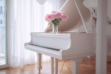 A white grand piano decorated with a vase of pink peonies.