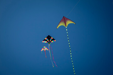 Tre aquiloni colorati che volano nel cielo blu
