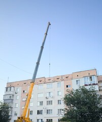 Construction crane in front of multi-story residential building on a sunny day &mdash; urban development, technical dynamics, and city infrastructure for architectural content, logistics projects