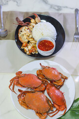 Whole Steamed Mud Crabs on a White Plate, and Picked Mud Crabs with Rice and Dipping Sauce on a Black Plate