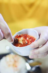 Person Dipping a Crab Leg into a Lifted Sauce Bowl