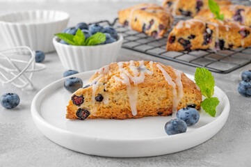 Blueberry scones with lemon glaze on top on a gray concrete background. Delicious breakfast.