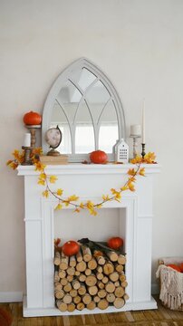 White fireplace with pumpkins, fall leaves garland, and firewood inside