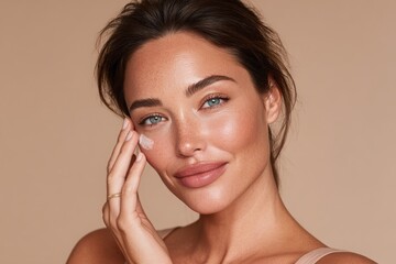 A beautiful young woman with glowing skin applying a skincare product to her face.