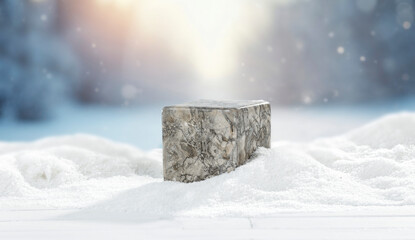 Winter landscape with fresh white snow and stone pedestal with copy space for product placement or text. Blurred background of snow-covered trees and blue winter sky and sunlight.
