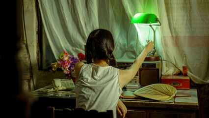 Young woman reaching for the lamp in a cozy, nostalgic indoor setting.
