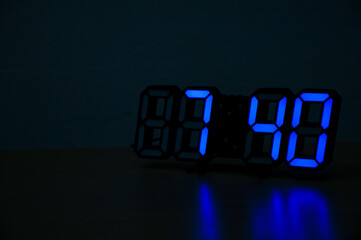 A close-up shot of a modern digital clock with glowing blue LED numbers showing the time 07:40, set against a dark background, highlighting the concept of time, technology, and the night.