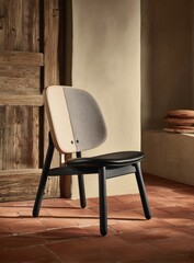 A modern, minimalist chair with a light beige and gray upholstered back and a black wooden frame sits on a terracotta tile floor in a rustic-style room.