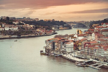 Fototapeta premium Overlooking the vibrant city as the light fades, the Douro River reflects the colors of the sky near the Dom Luis I bridge in Porto, Portugal